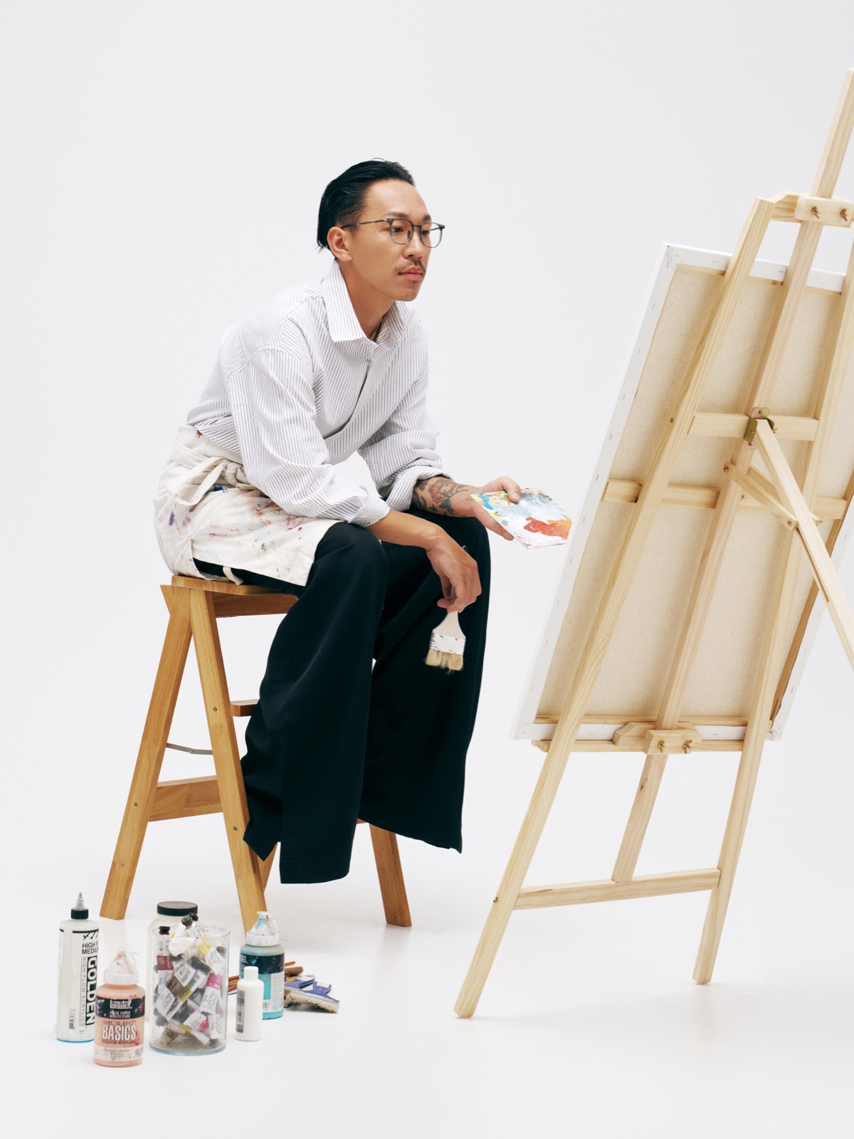 Male model wearing MUJOSH eyewear in an artist studio campaign image